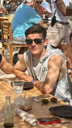 a man in sunglasses sitting at a wooden table