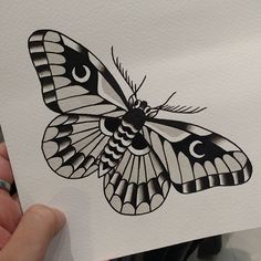 a drawing of a butterfly is shown in black and white, while someone holds it up to the camera