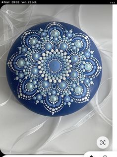 a blue painted rock with white dots and circles on it, sitting on a white background