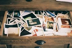 a drawer filled with pictures and papers on top of a wooden table next to a lamp