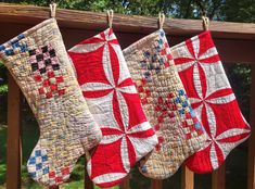 three quilted christmas stockings hanging from a wooden rail