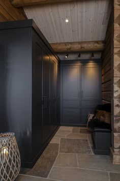 a room with some black cabinets and lights on the ceiling, along with a stone floor