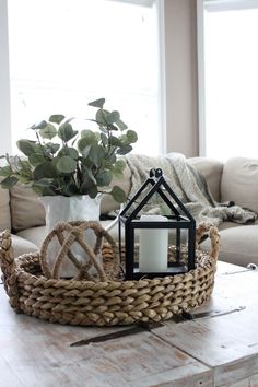 a living room table with a basket on top of it and a candle in the center