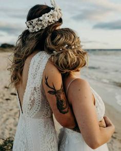 two women standing next to each other at the beach with tattoos on their arms and shoulder