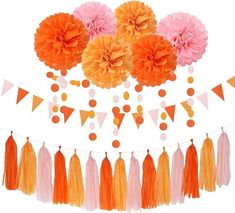 an orange and pink party decoration with tissue pom poms