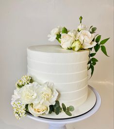 there is a white cake with flowers on the top and bottom, sitting on a plate