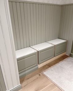 an empty room with wooden floors and gray cabinets on the wall, next to a white rug