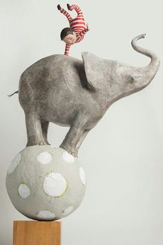 a statue of a boy riding on top of an elephant's head with his trunk in the air