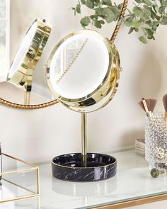 a mirror sitting on top of a table next to a brush holder and potted plant