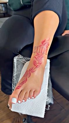 a woman sitting on top of a chair with her foot covered in red ink and tattoos