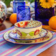 a table topped with plates and cups on top of a wooden table next to oranges