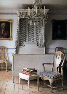 a room with two chairs, a bed and a chandelier