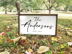 a sign that is in the grass near some leaves and trees, with the words the andersons written on it