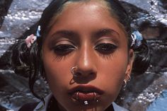 a woman with piercings on her nose and nose ring in front of a rock wall