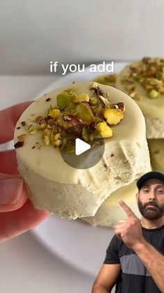 a man is holding a piece of cake with pistachio toppings on it