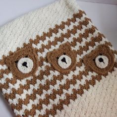 a brown and white crocheted blanket with bears on it