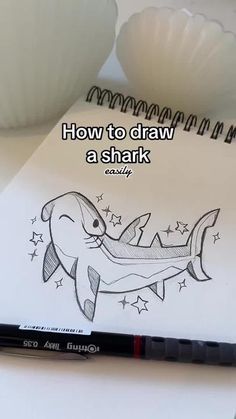 a notebook with a drawing of a shark on it and the words how to draw a shark