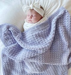 a baby wrapped in a blanket on top of a bed