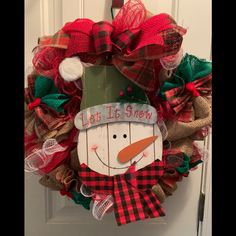 a christmas wreath with a snowman wearing a green hat and red plaid bow on the front door