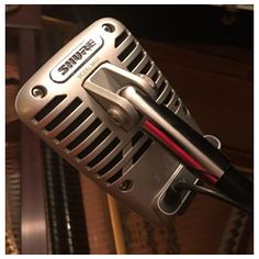 a close up of a microphone on top of a piano case with other musical instruments in the background