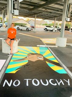 a woman is sitting on a bench in a parking lot with an image painted on the ground