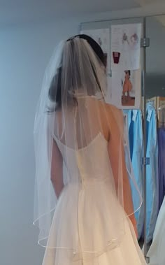 the back of a bride's wedding dress as she stands in front of a mirror