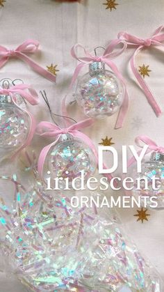 three clear ornaments with pink bows and glitter on them are sitting on a white sheet