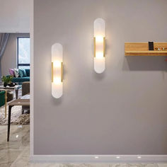 two lights on the wall next to each other in a room with grey walls and furniture