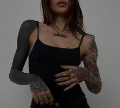 a woman with tattoos on her arms and arm is holding something in one hand while wearing a black tank top