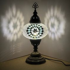 a lamp that is sitting on top of a table in front of a white wall