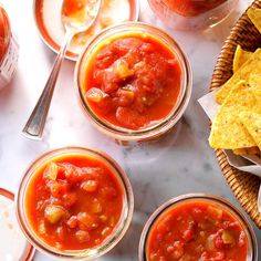 three small jars filled with salsa and tortilla chips on a marble counter top