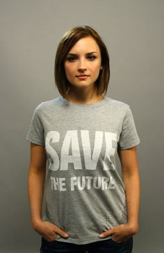 a woman standing in front of a gray wall with the words save the future on it