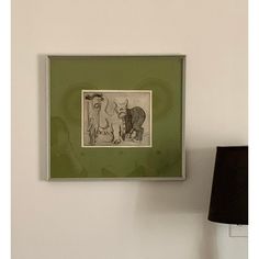 a green frame hanging on the wall next to a lamp with a dog and cat drawn on it