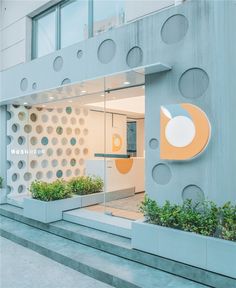 the entrance to an office building with planters on each side and circular holes in the wall