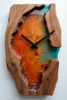 a clock made out of wood with orange and blue paint on the face, sitting on a white wall