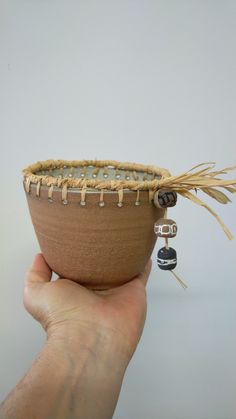 a hand holding a small bowl with a feather on it