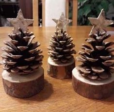 three pine cones sitting on top of a wooden table next to each other with stars