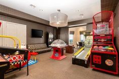 a room that has some arcade machines and couches in it with a television on the wall