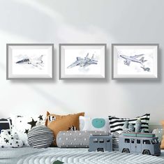 three framed pictures hang on the wall above a child's bed with toys in it