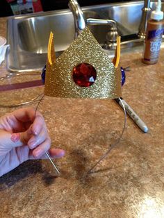 a person is making a crown out of paper and some scissors on a counter top