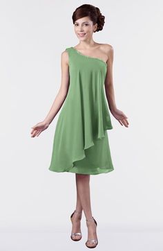 a woman in a green dress posing for the camera with her arms out and hands on her hips