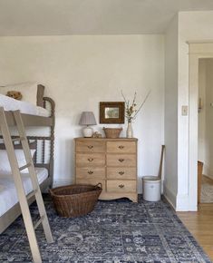 a bedroom with two bunk beds, a dresser and a rug on the floor in front of it