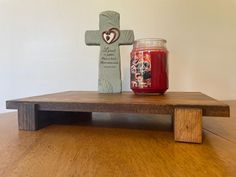 a candle sits on a wooden table next to a crucifix with a heart