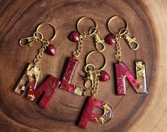 the letters are made out of gold and red marbles on a wooden surface with keychains