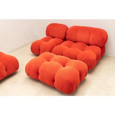 an orange couch and footstool sitting next to each other on a white floor