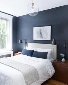 a bedroom with blue walls and white bedding