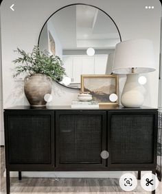 a large mirror sitting on top of a wooden dresser next to a lamp and potted plant