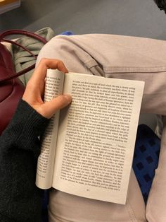 a person sitting down reading a book with their hands resting on the back of his leg