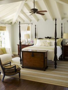 a bedroom with a bed, chair and ceiling fan in the middle of the room