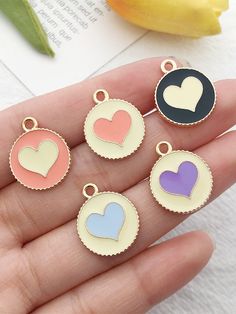 four heart shaped charms sitting on someone's hand